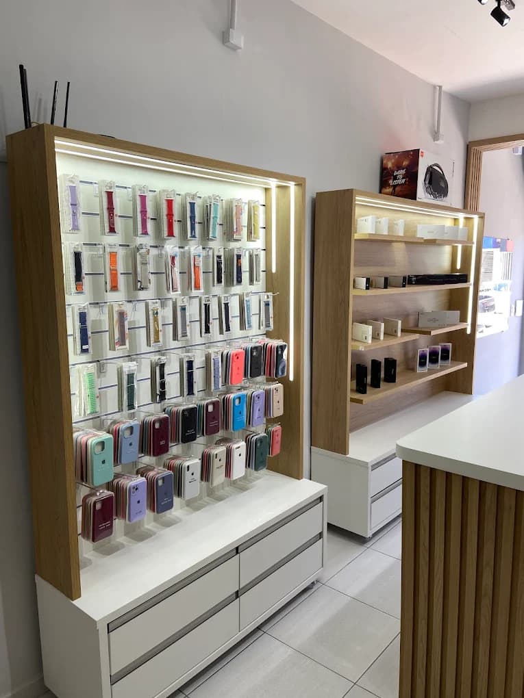 Parede de acessórios da Pró iPhones com pulseiras de Apple Watch e capas de iPhone organizadas em expositor iluminado